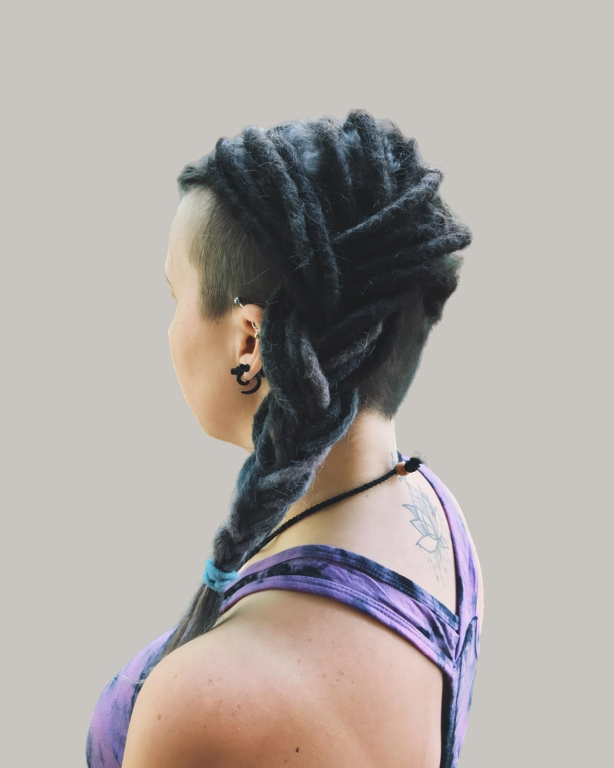 Woman with locs braided back over a shaved side, seen from behind