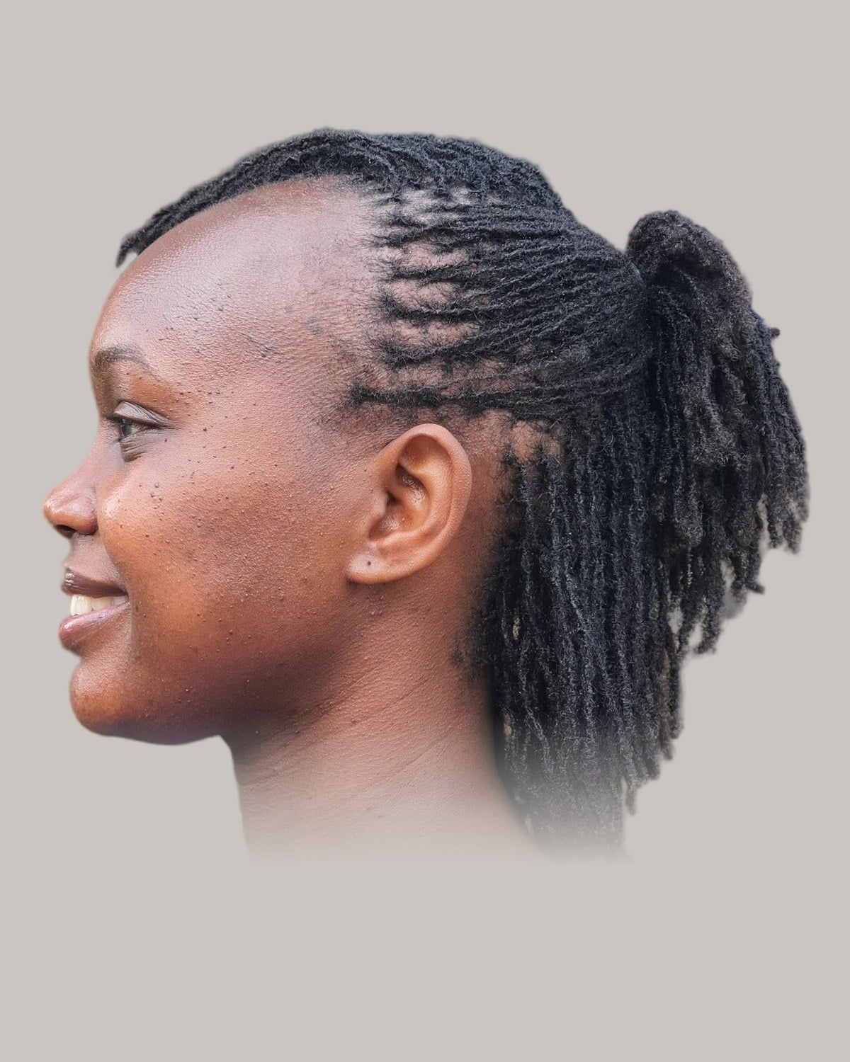 Woman with small locs pulled back into a ponytail, in profile