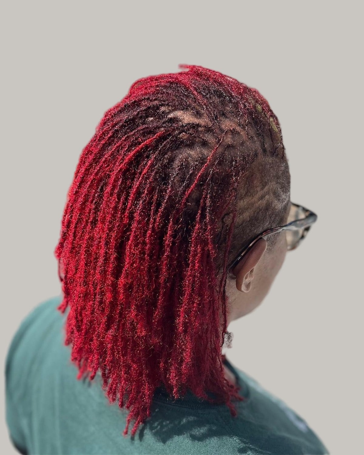 Woman with red microlocs pushed back, seen from the side