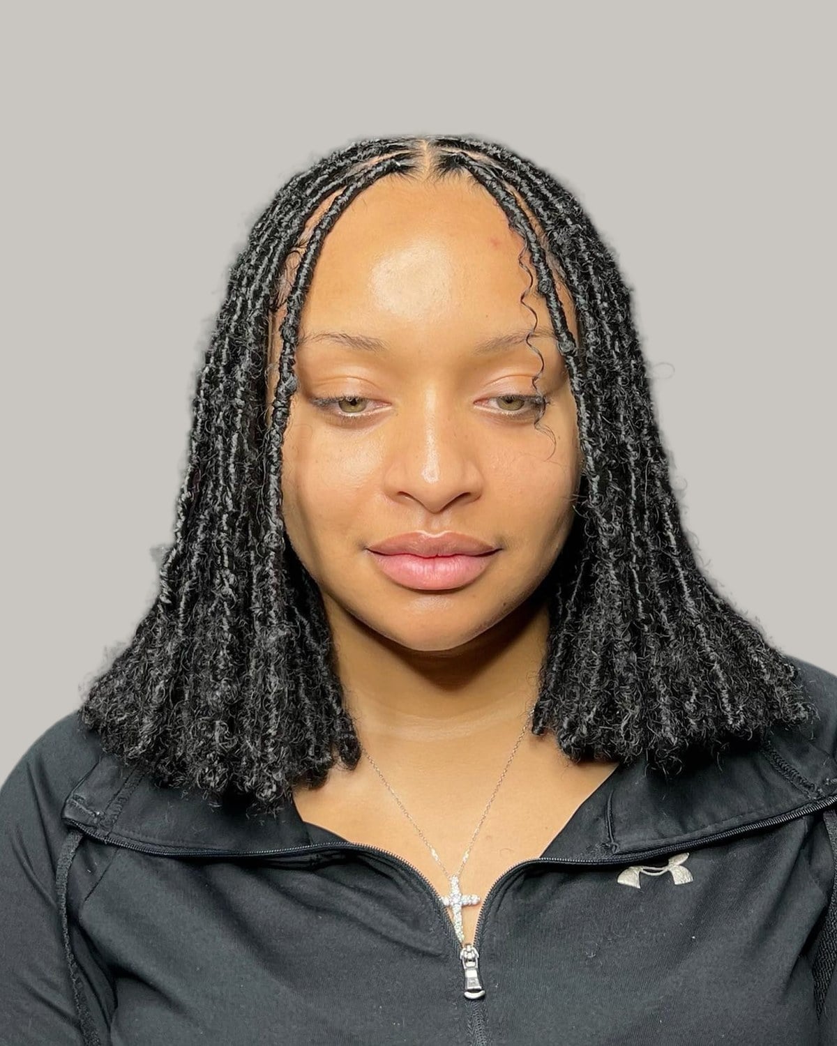 Woman with shoulder-length black butterfly locs and a middle part, seen from the front