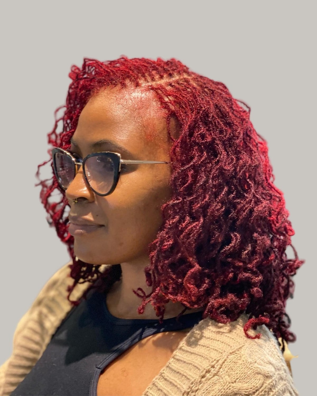 Woman with deep red curly locs and glasses