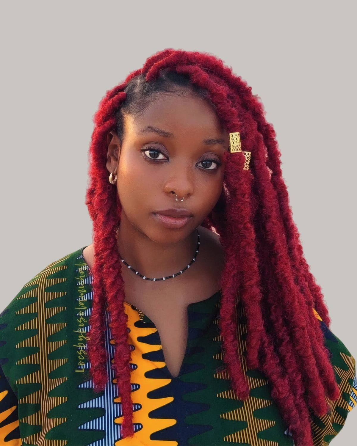 Woman with long crimson soft locs, standing outdoors