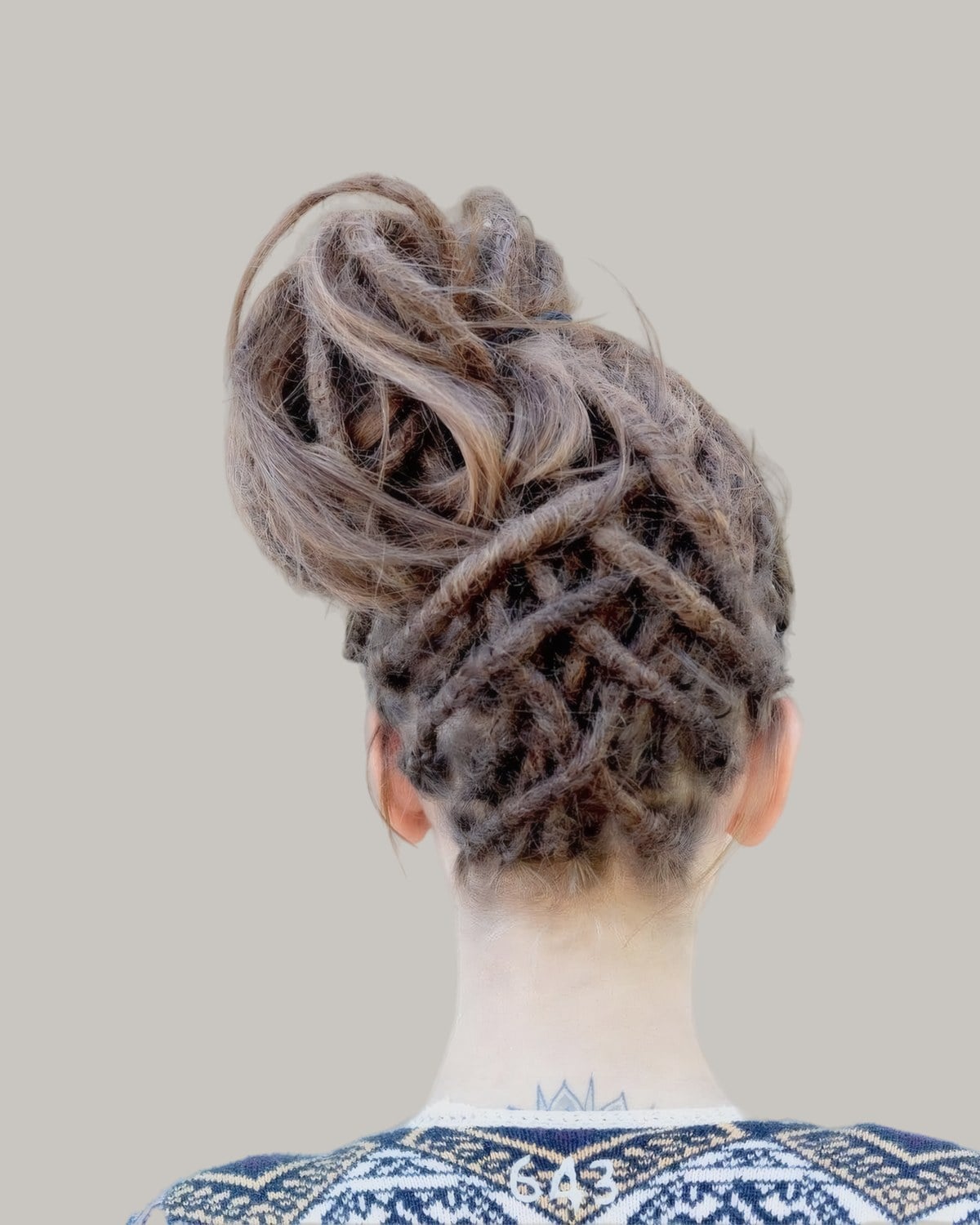 Back of a head with locs wound into a lattice under a bun