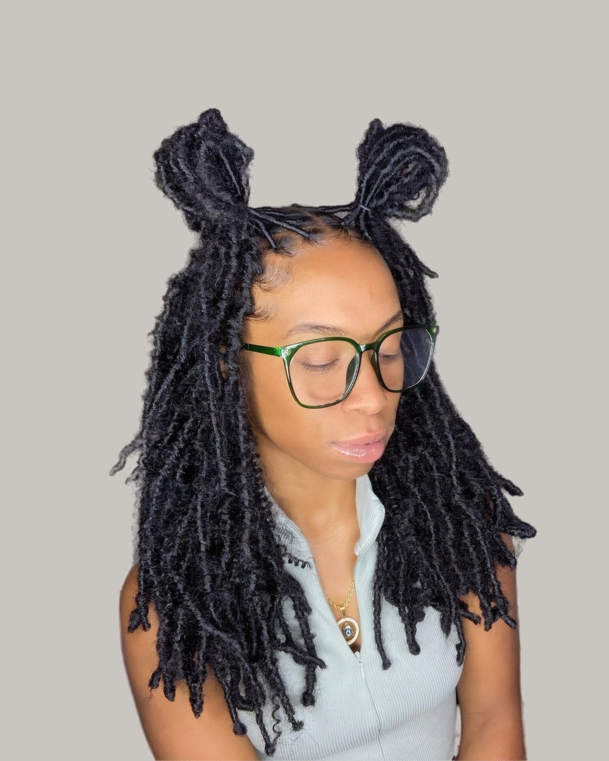 Woman with two small space buns on long black locs, and glasses