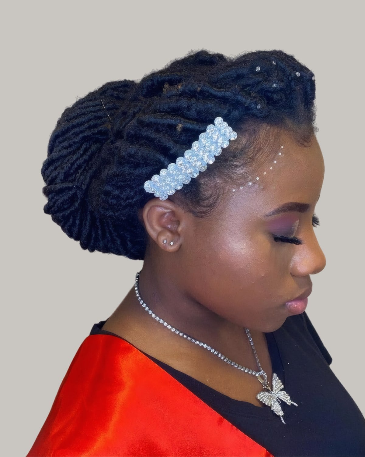 Woman with black locs piled into a big bun with a pearl clip