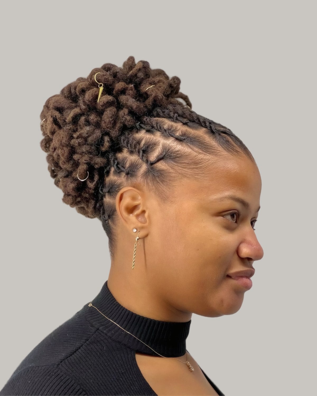 Woman with a brown loc puff bun and neat parts at the side