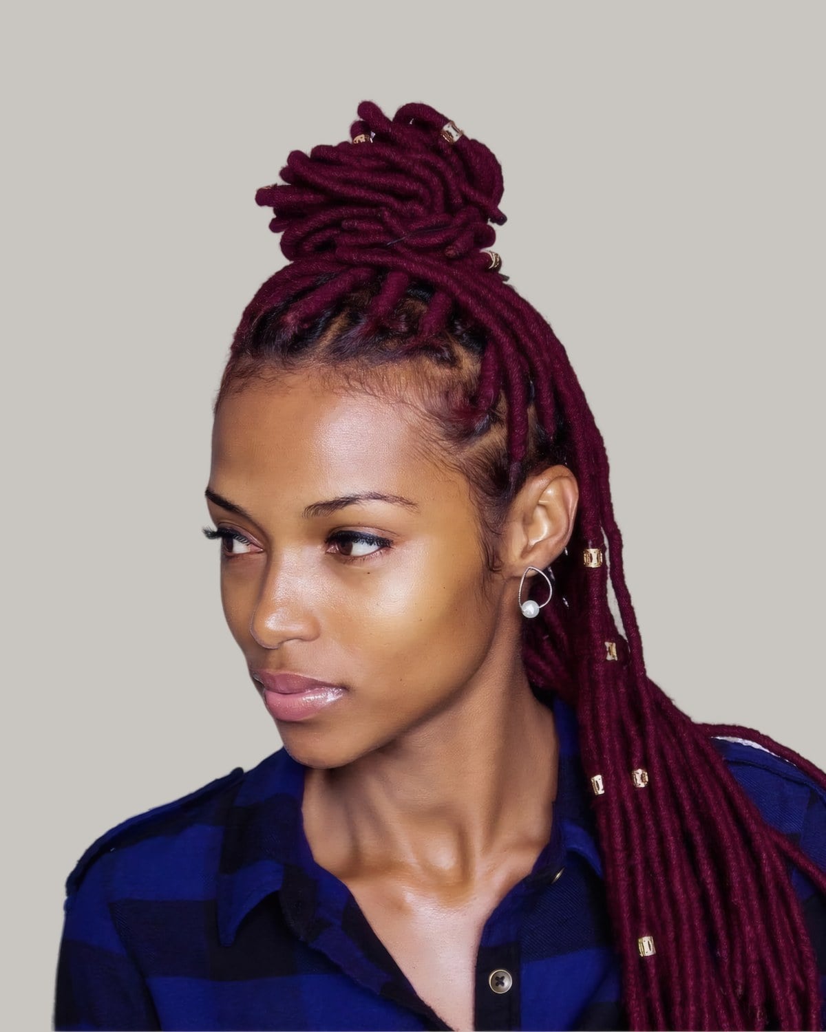 Woman with burgundy locs, the top twisted into a high knot and the rest down