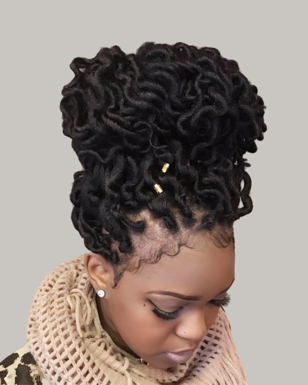 Woman with curly locs piled into a high bun with gold cuffs