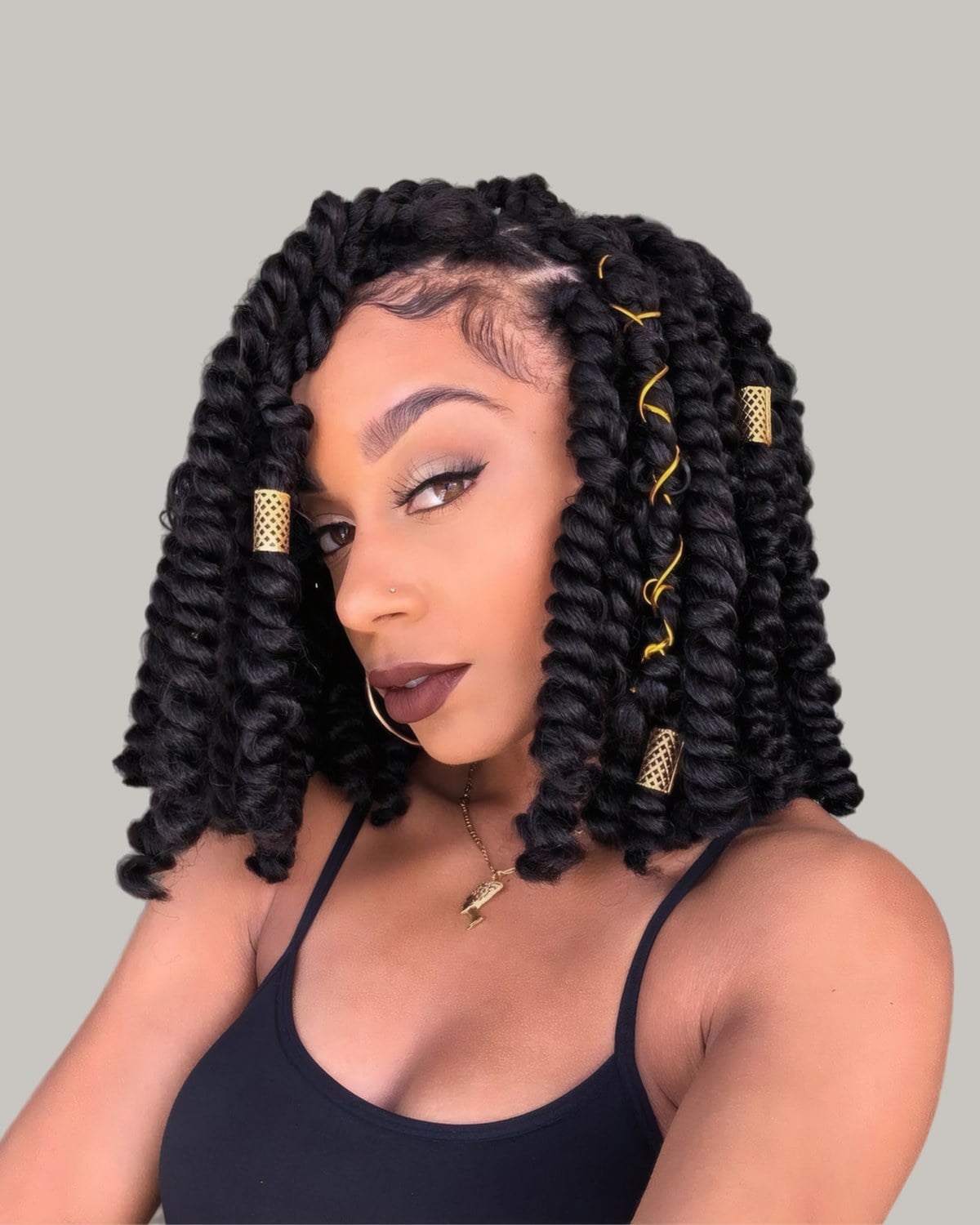 Woman with a black loc bob curled at the ends, with gold cuffs