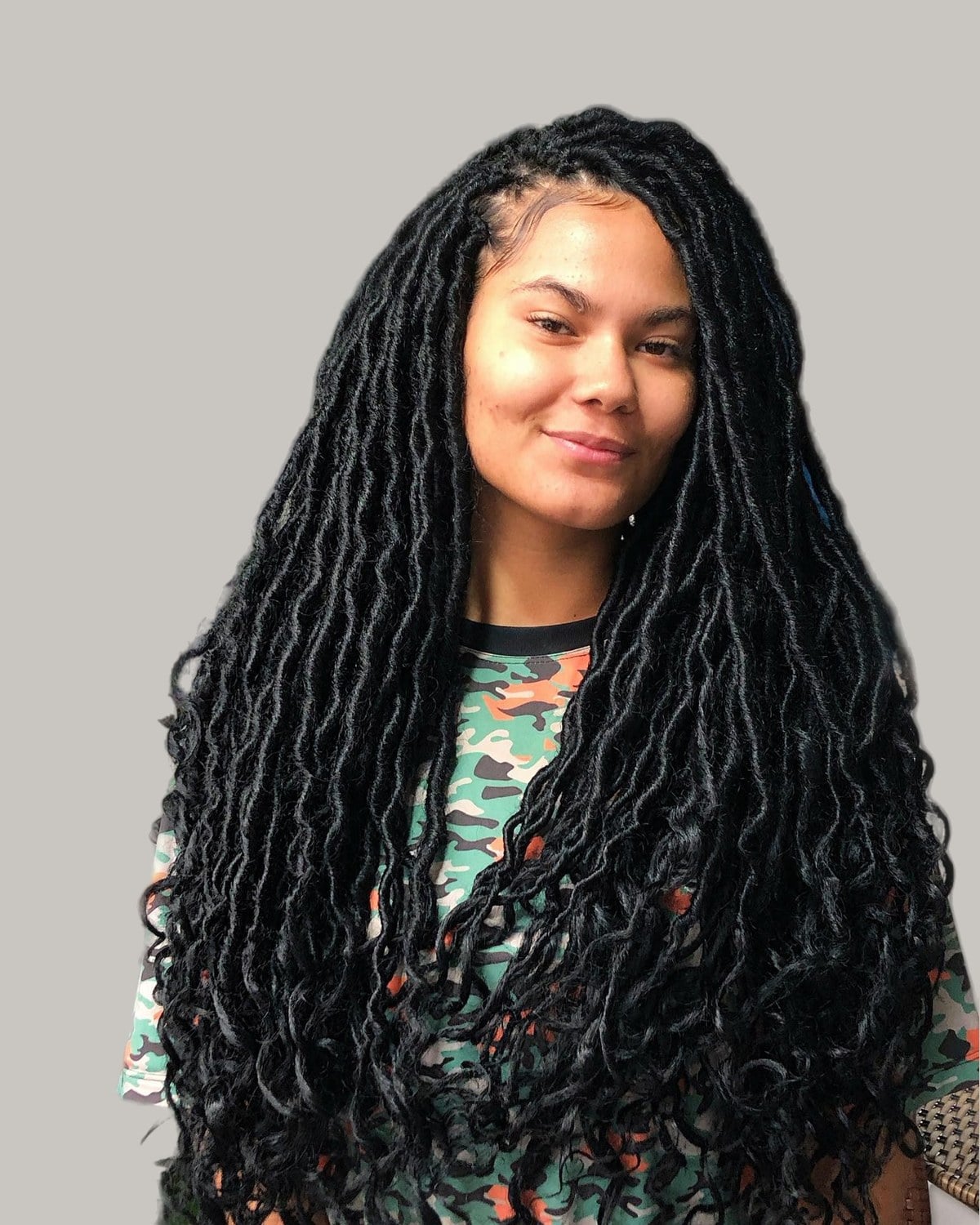 Smiling woman with long wavy black faux locs
