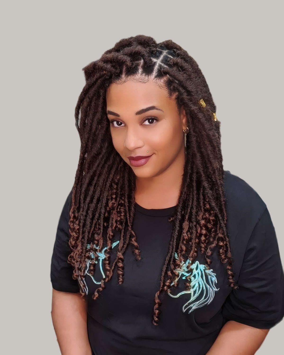Smiling woman with long brown and black locs with curly ends