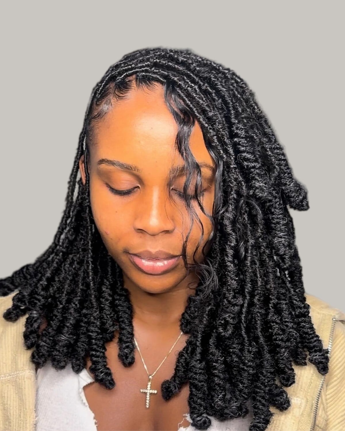 Woman with shoulder-length black locs curled at every end, looking down