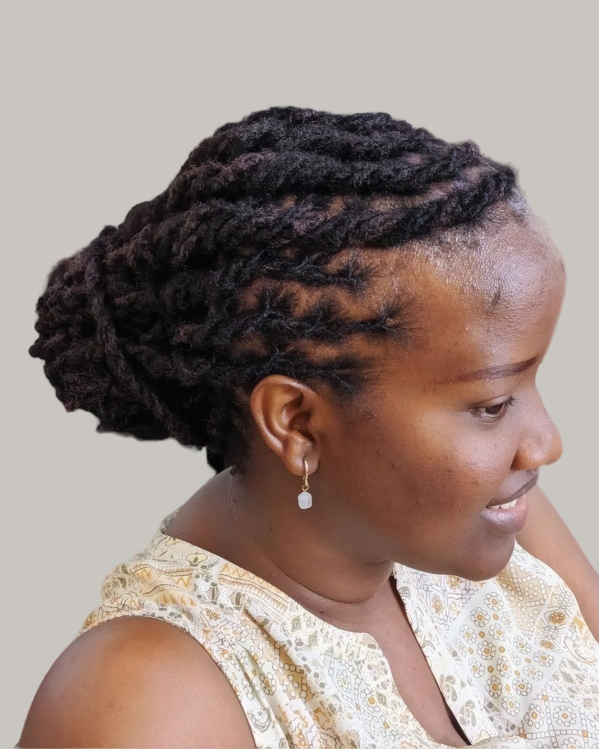 Woman with locs cornrowed back into a bun, in profile
