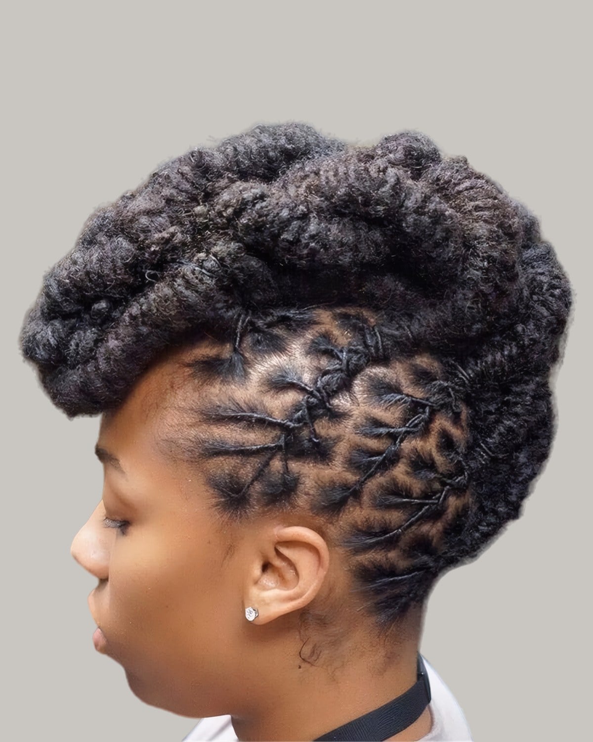 Woman with locs braided flat up the side of her head into a rolled loc mohawk, in profile