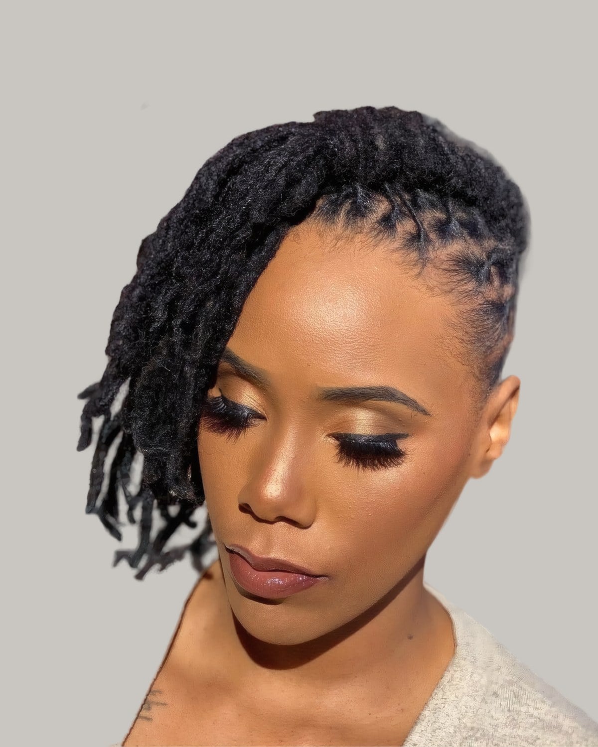 Woman with short locs curled on top and swept forward