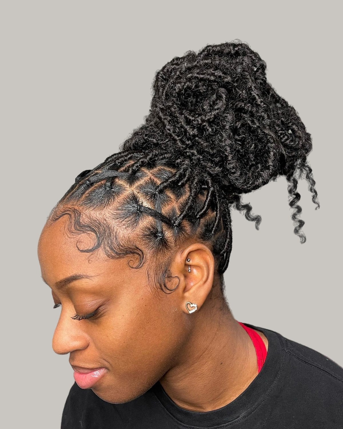 Woman with locs criss-crossed at the front and piled into a bun