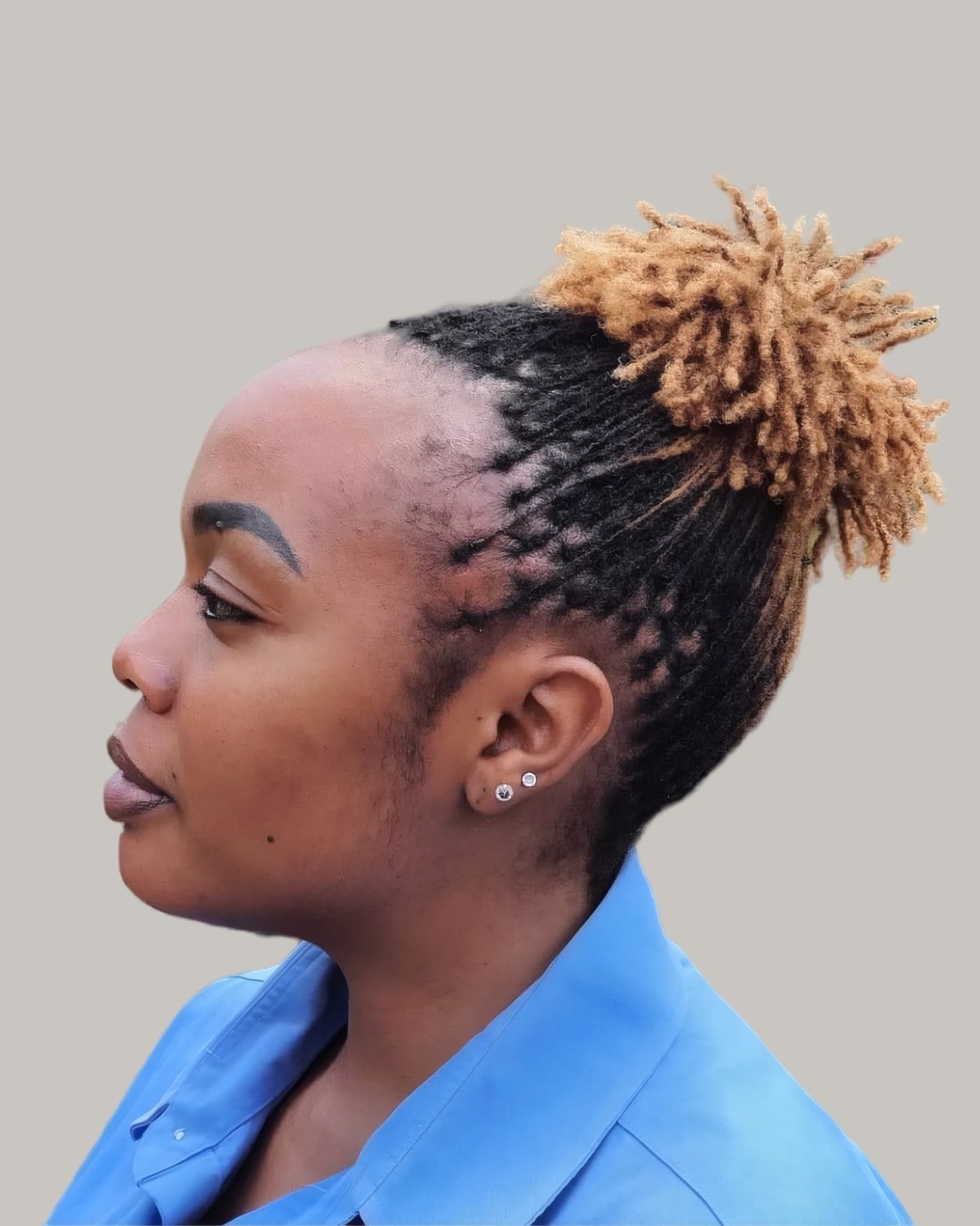 Woman with short locs in a high puff with sandy tips, in profile