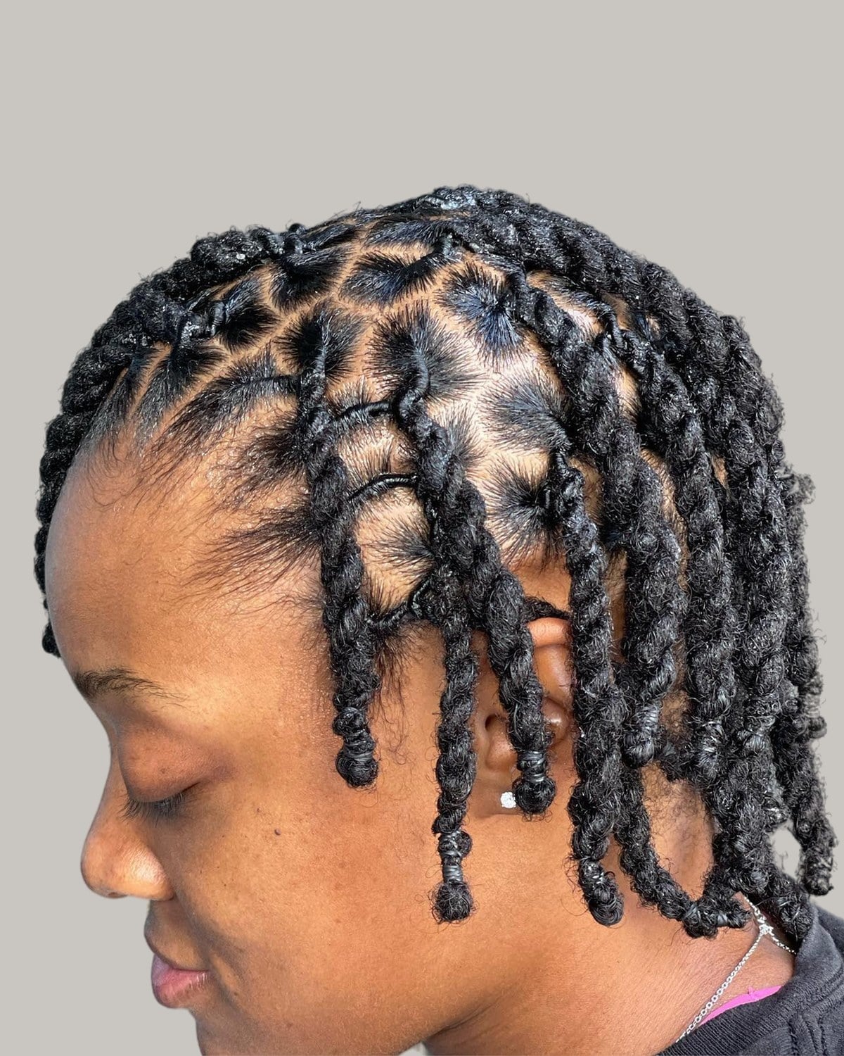 Woman with short black locs curled under at the ends, seen from the side