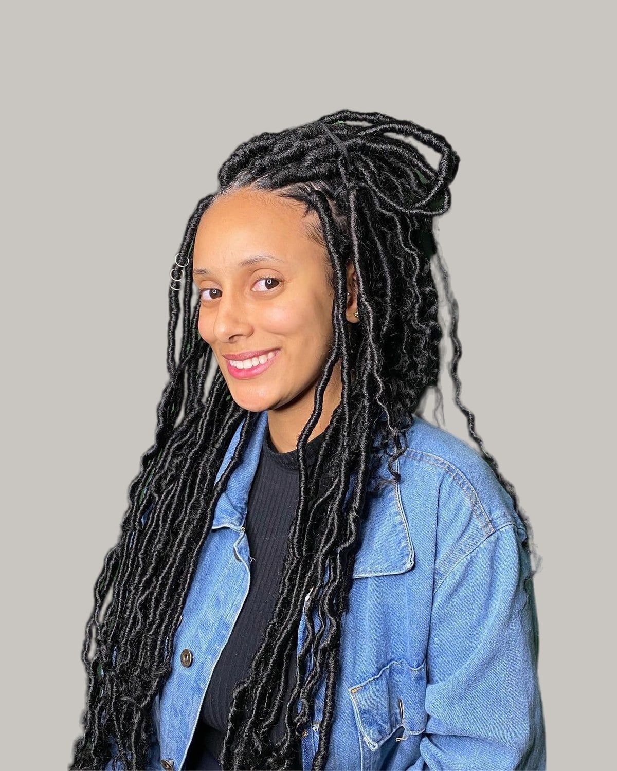 Smiling woman with long black synthetic locs and a jean jacket