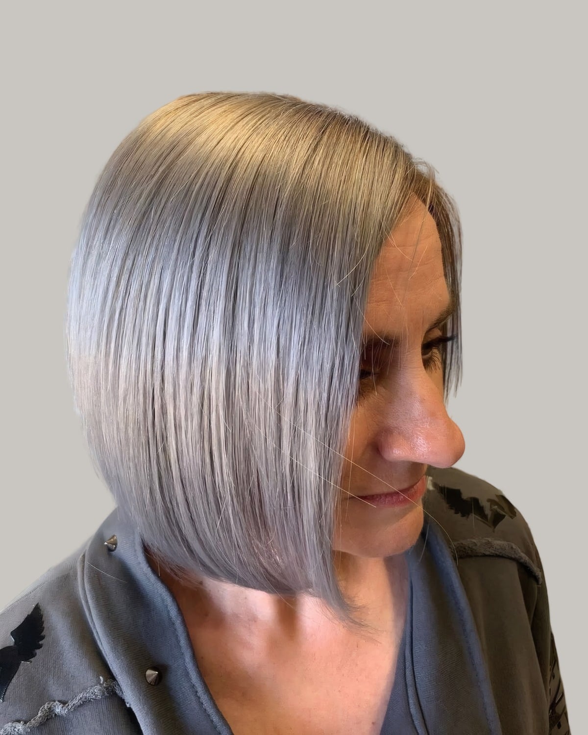 Woman with a sleek silver A-line bob, looking down