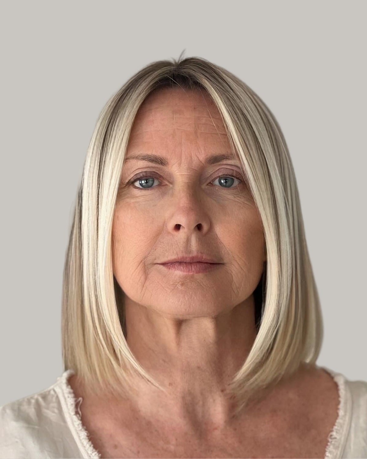 Woman with a blunt platinum cut to the shoulders and a center part