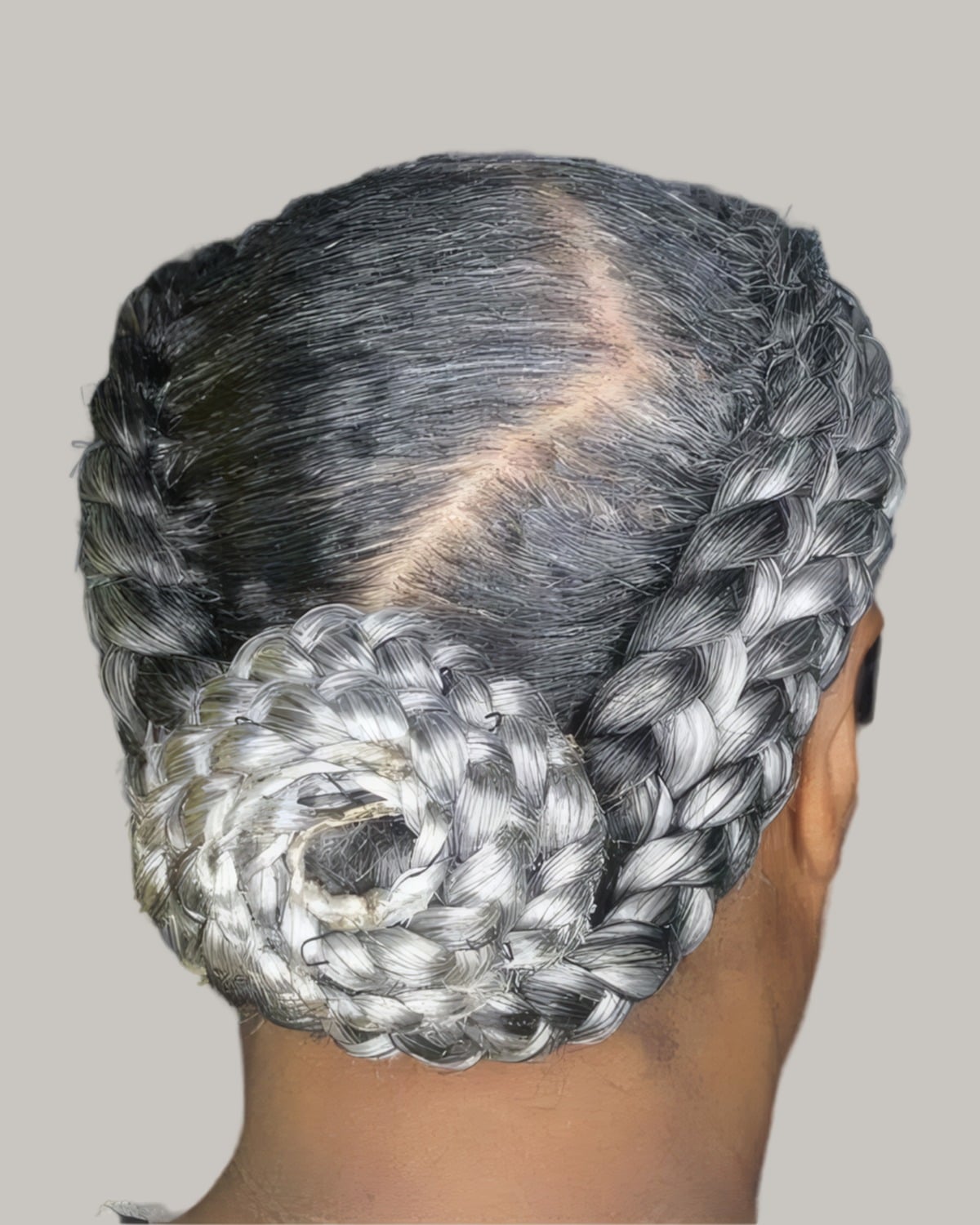 Gray braids coiled into a low bun, seen from behind