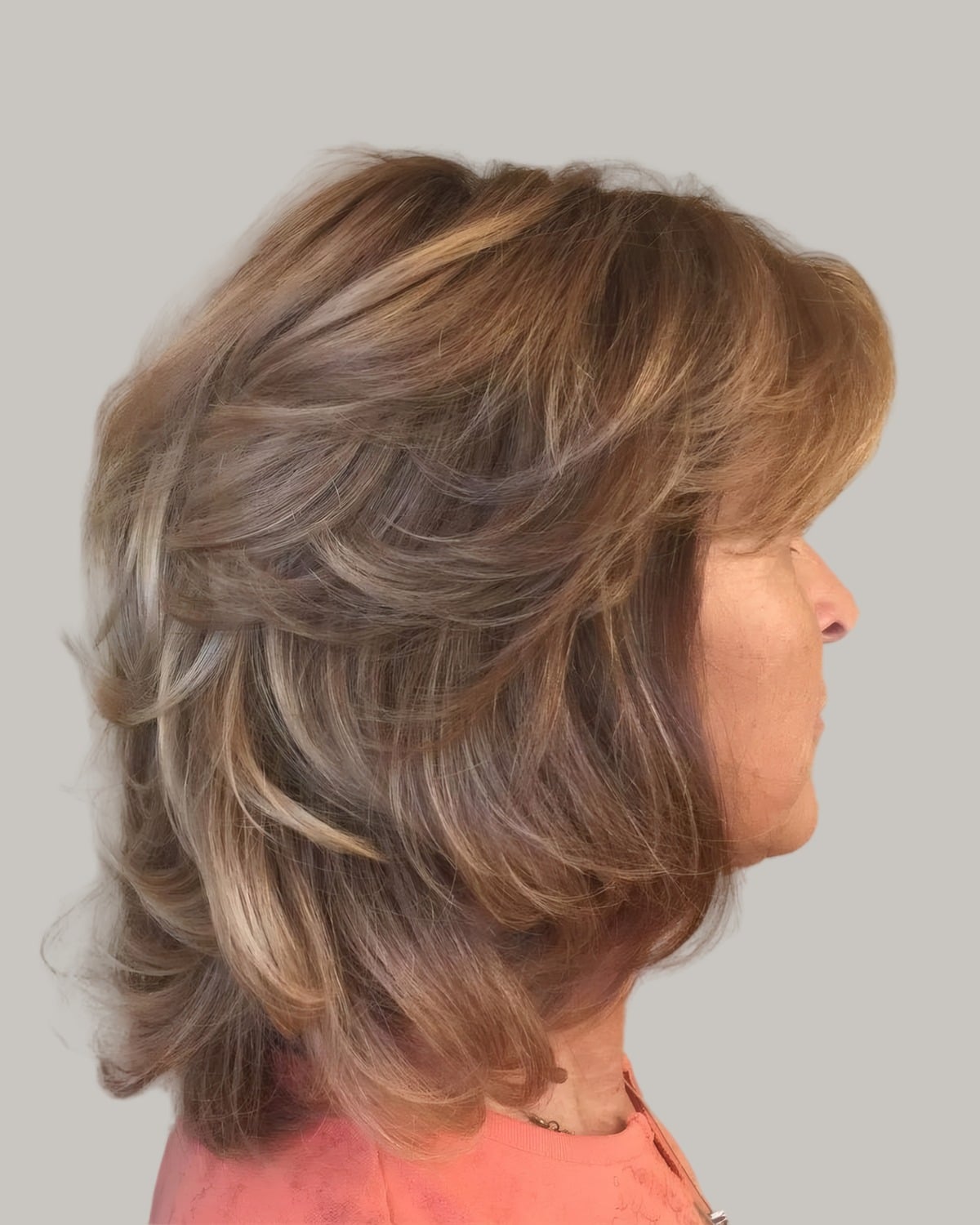 Woman with feathered light-brown layers, seen in profile