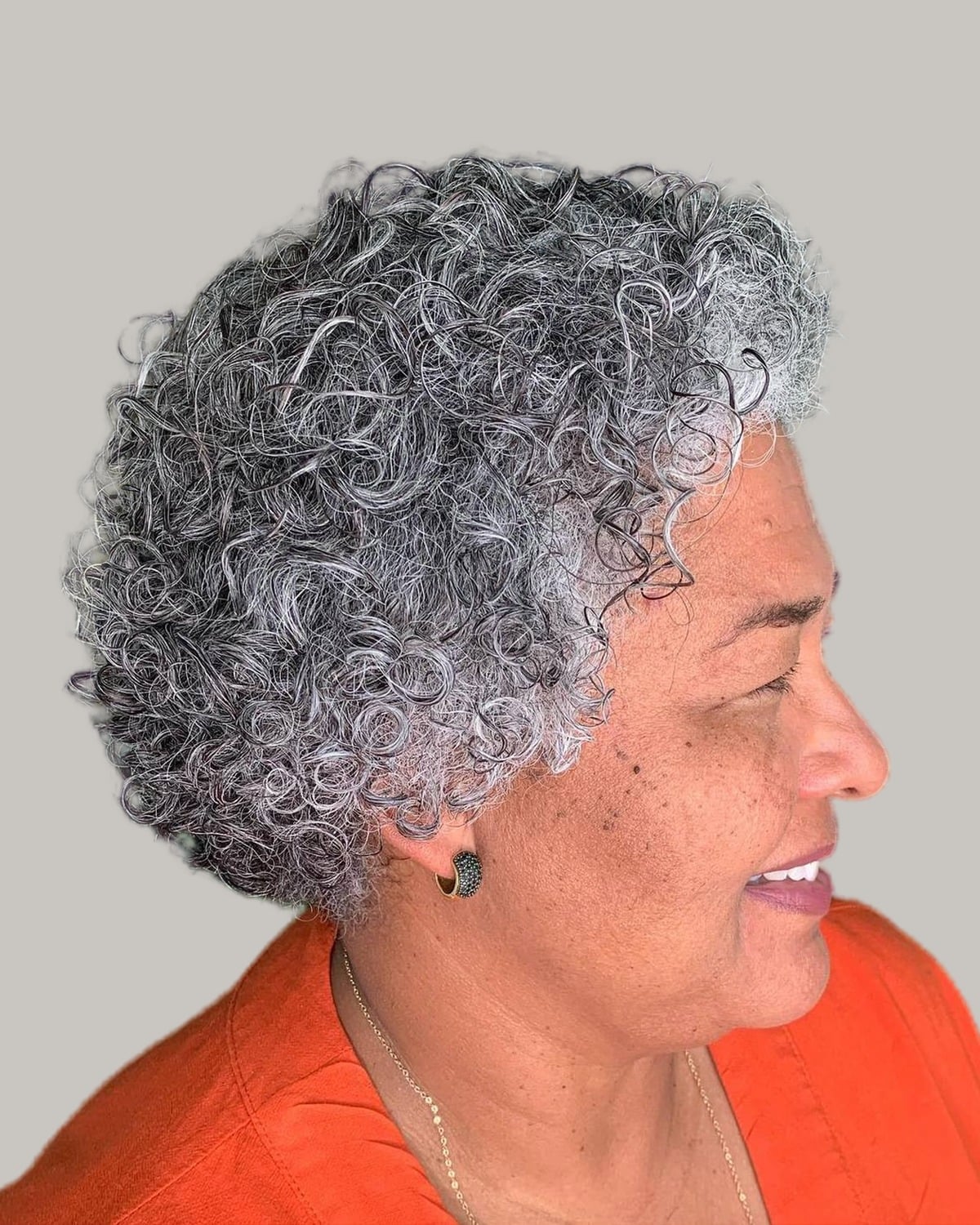 Smiling woman with a short gray coily crop, seen in profile
