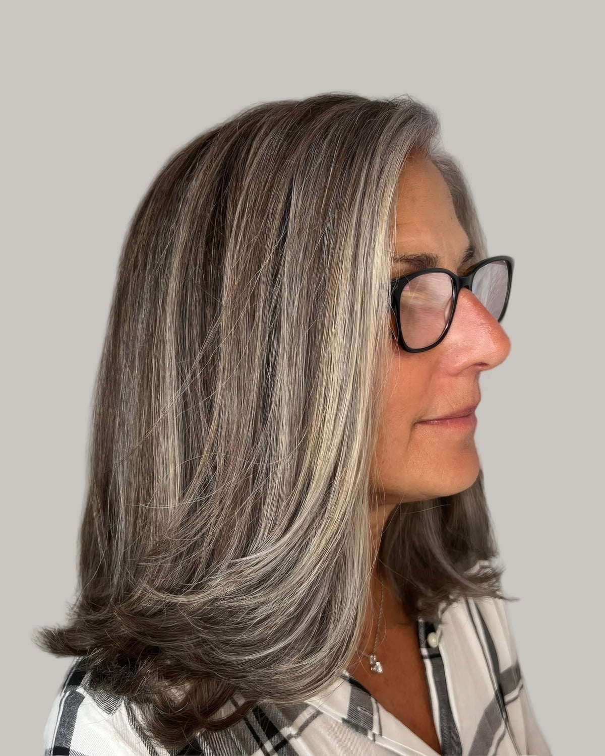 Woman with long gray-blended hair and dark glasses, seen from the side