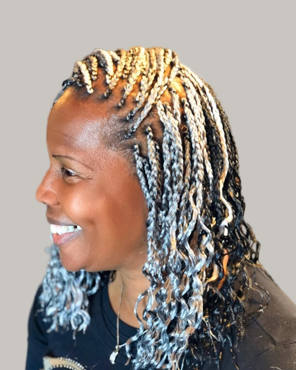 Smiling woman with gray and blonde braids with curly ends, seen in profile