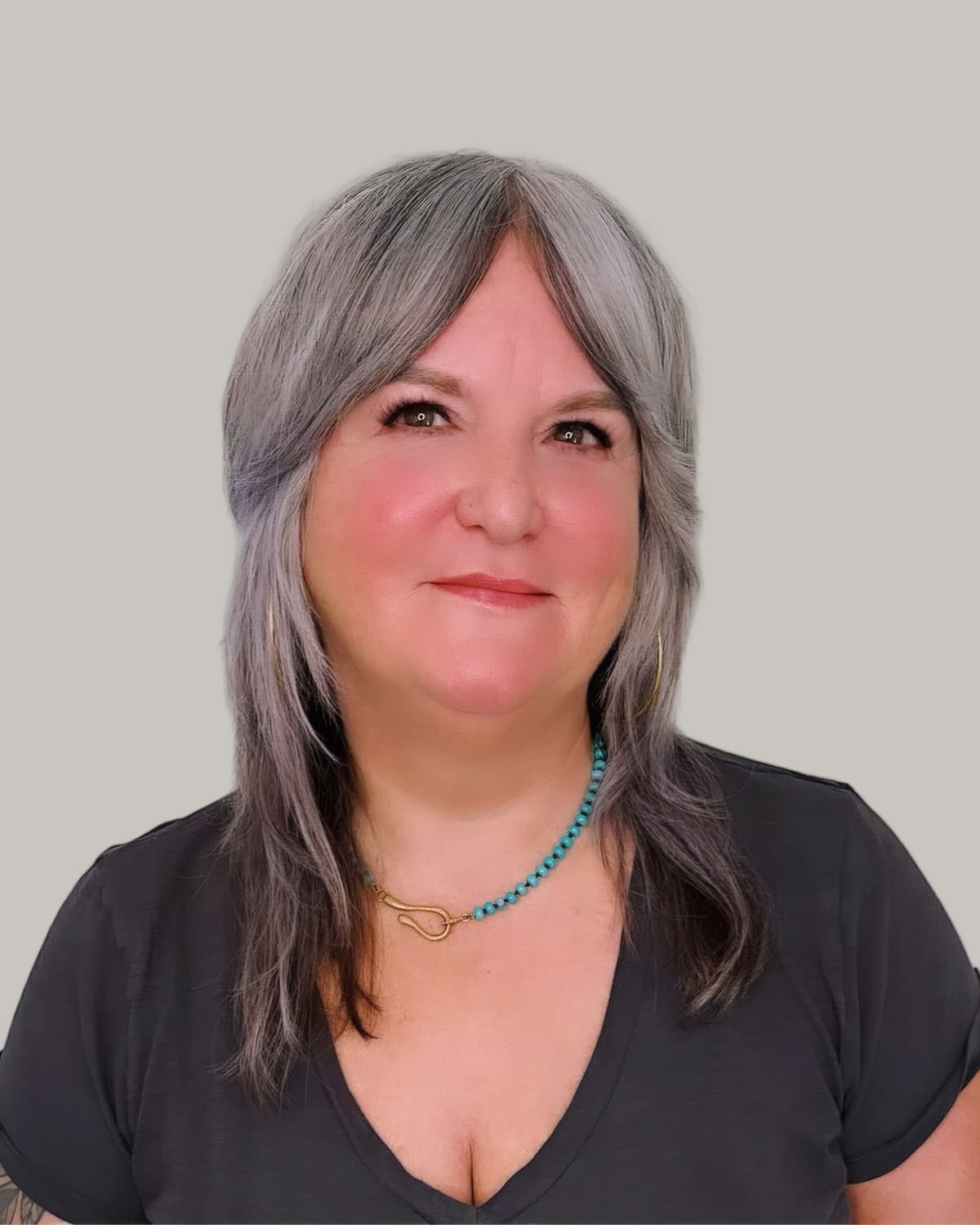 Woman with long gray hair and curtain bangs, a turquoise necklace