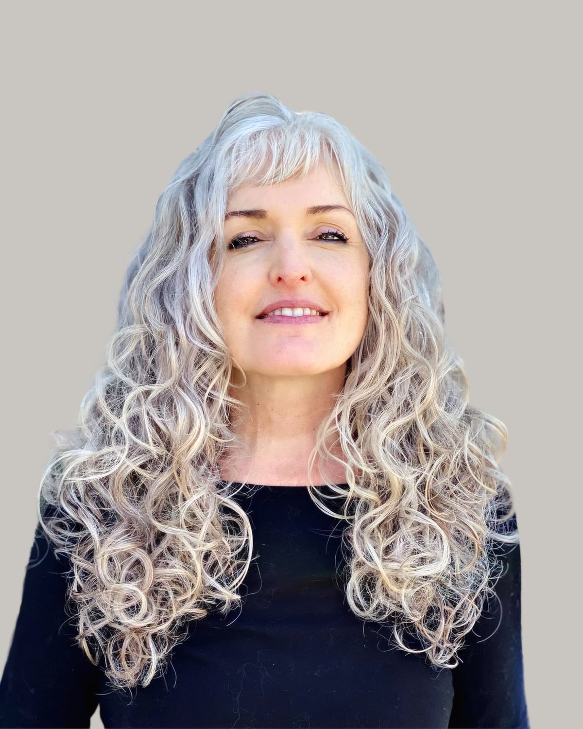 Smiling woman with long silver curls and wispy bangs