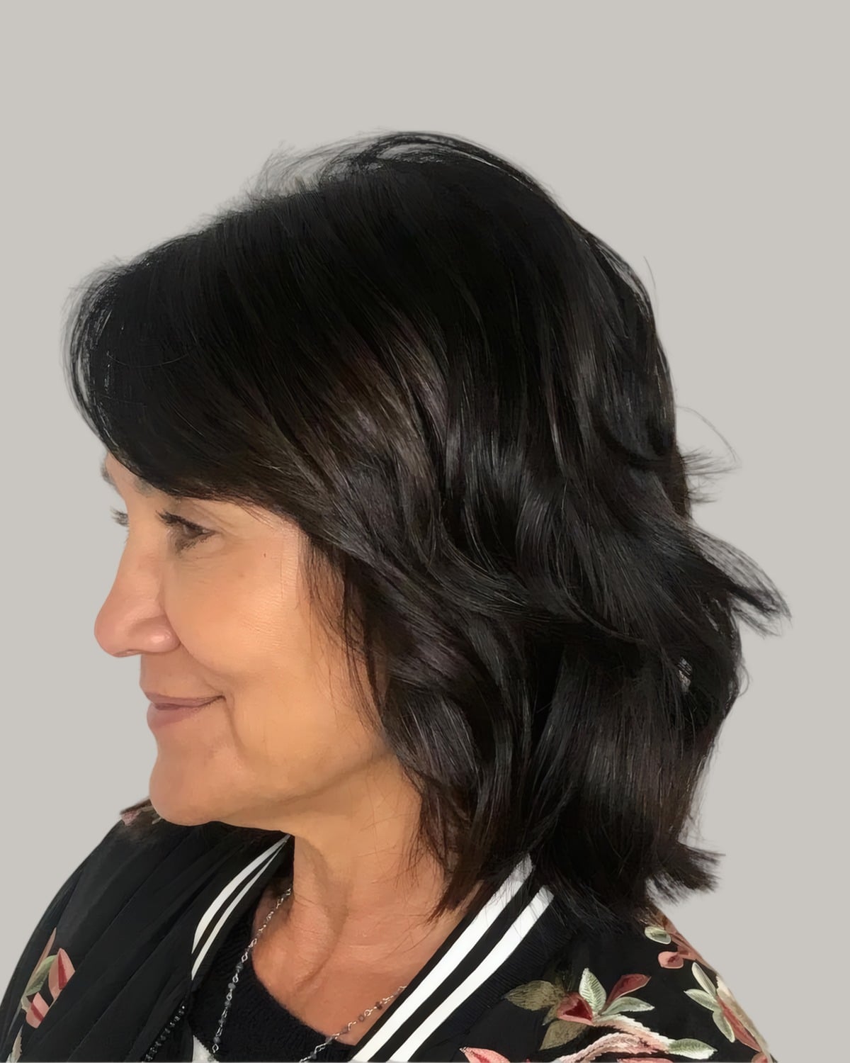 Woman with a black medium shag and a fringe, seen in profile