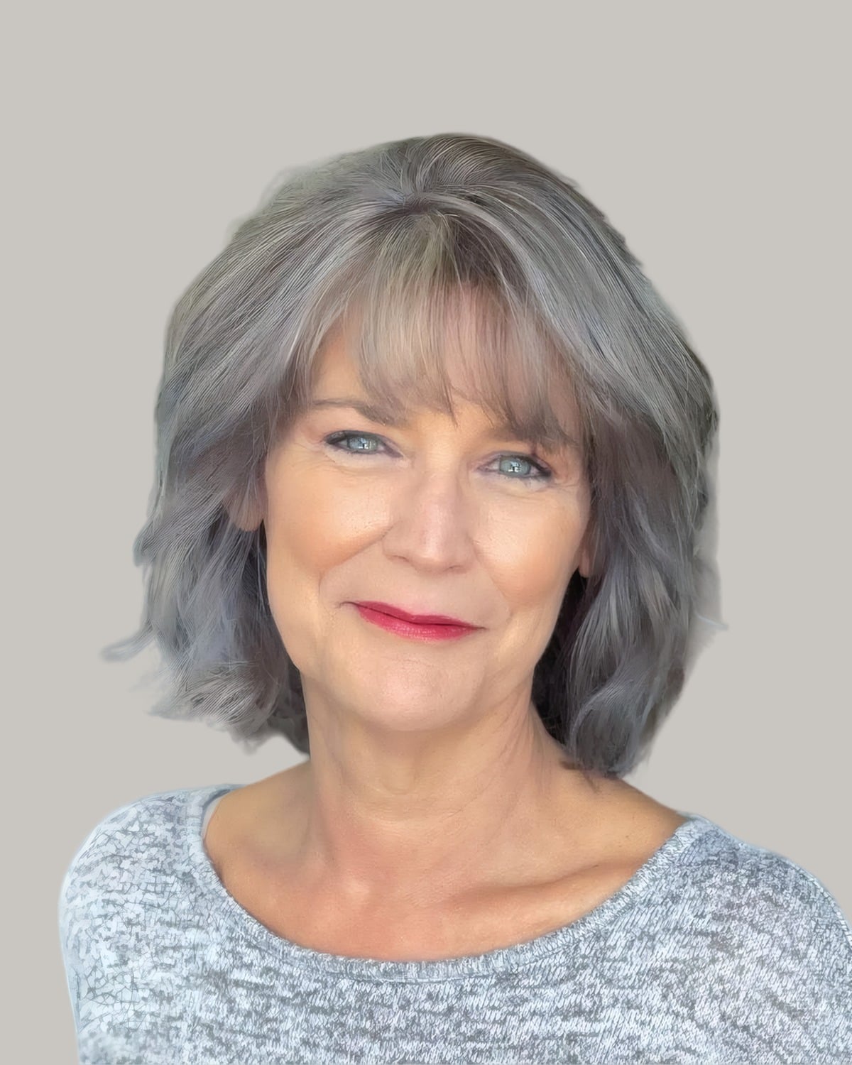 Smiling woman with shoulder-length gray hair and a full fringe