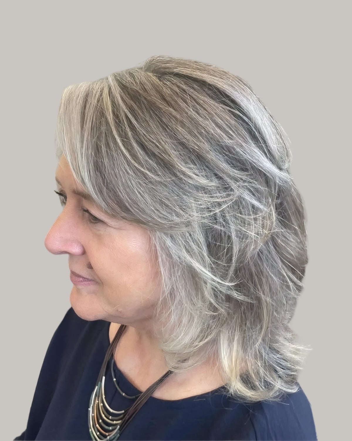 Woman with layered silver hair to the shoulders, seen from the side