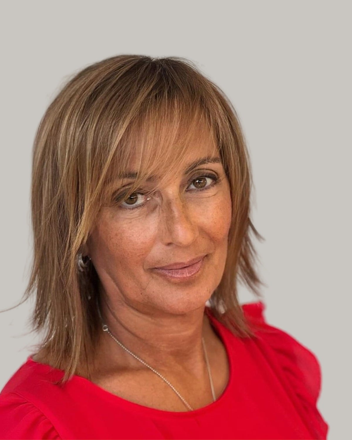 Woman with a light-brown shoulder-length shag and a fringe