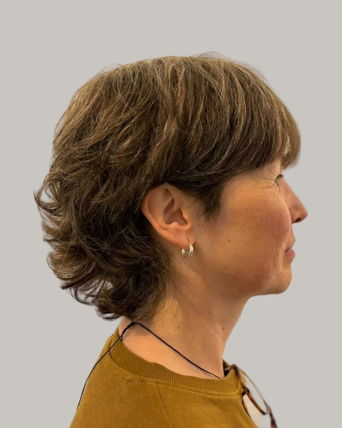 Woman with a short brown shag and a fringe, seen in profile