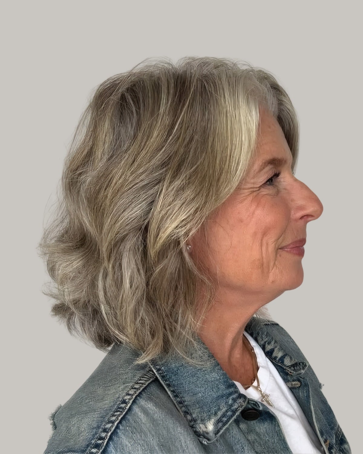 Woman with wavy gray-blonde hair to the shoulders, seen in profile