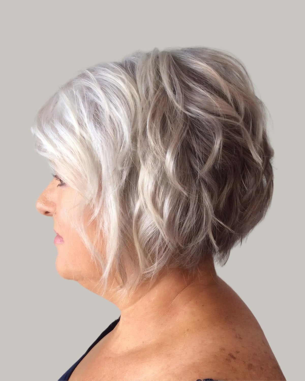 Woman with a wavy white and silver bob, seen in profile