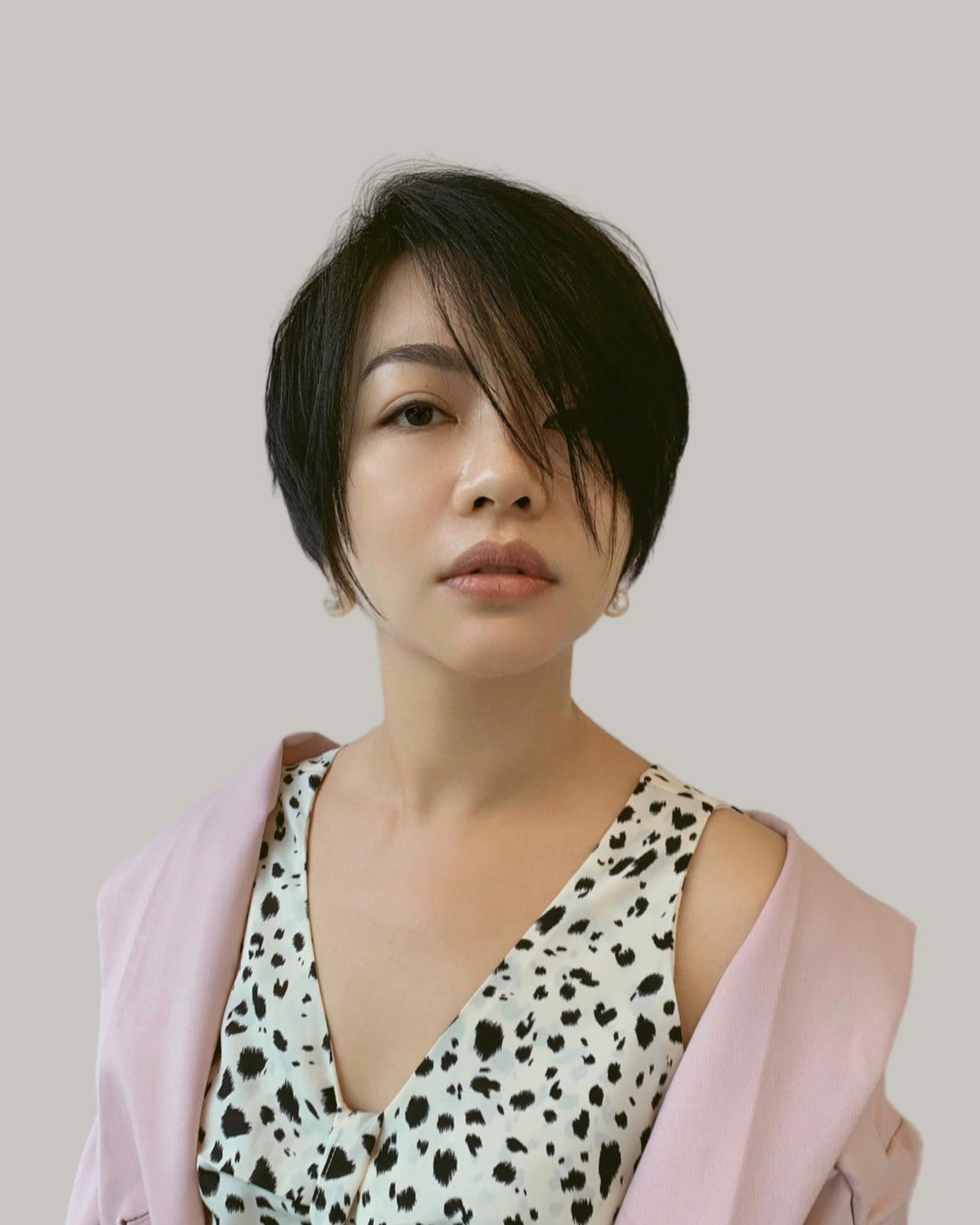 Woman with a black bixie haircut and a long side fringe, in a spotted top