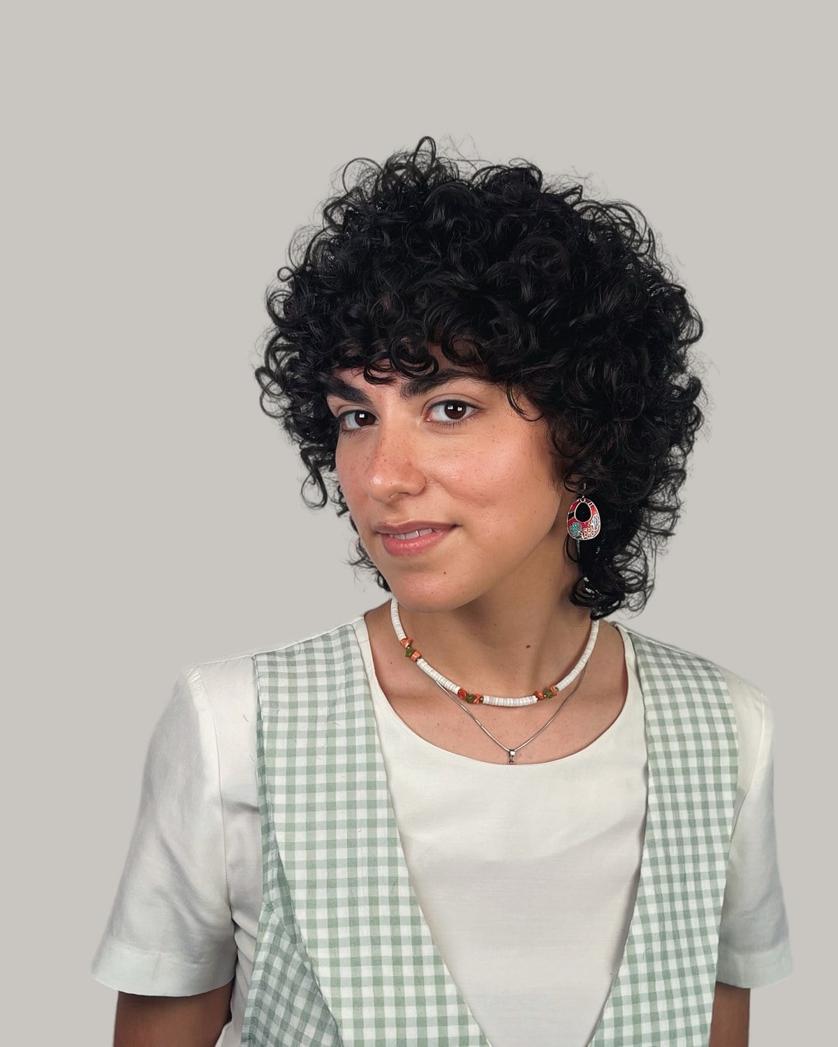 Woman with dark, curly layers and a curly fringe