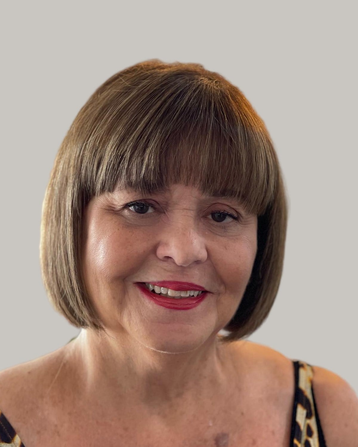 Smiling woman with a brown French bob and a full fringe