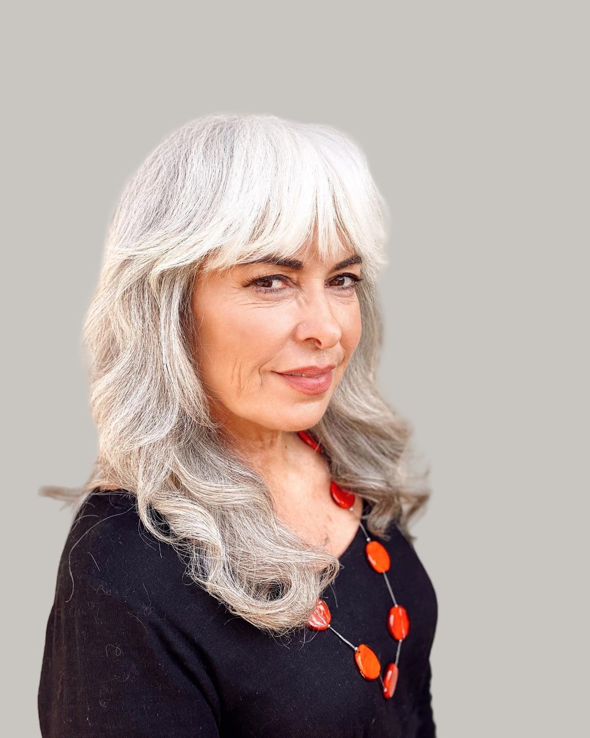 Woman with long silver waves and a full fringe that curves down at the sides