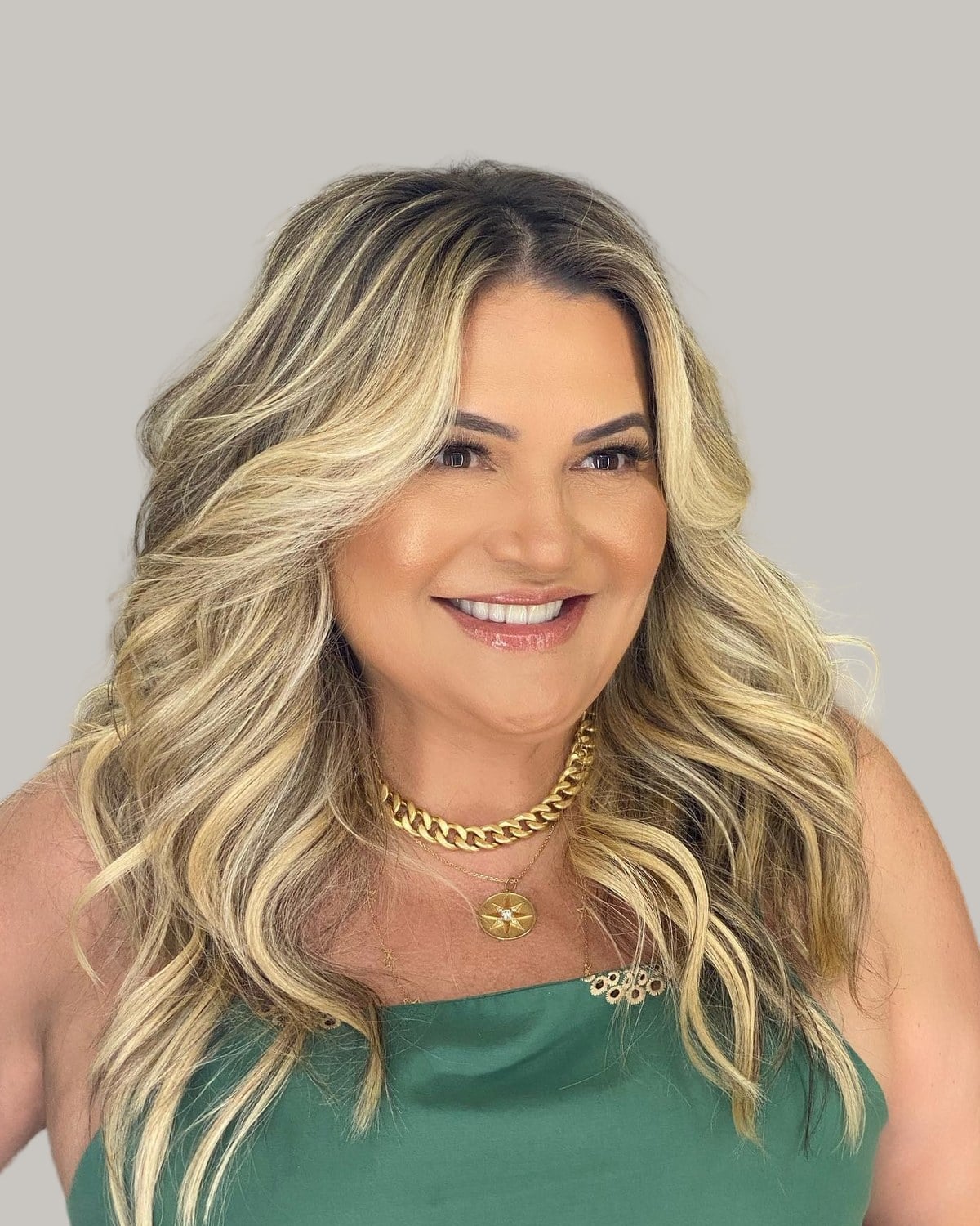 Smiling woman with long blonde waves and face-framing layers