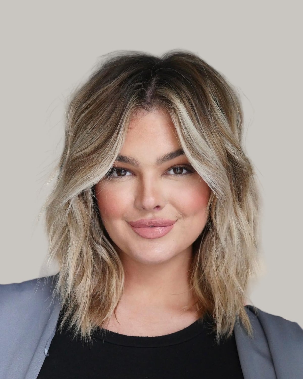 Smiling woman with blonde shoulder-length layers and a center part