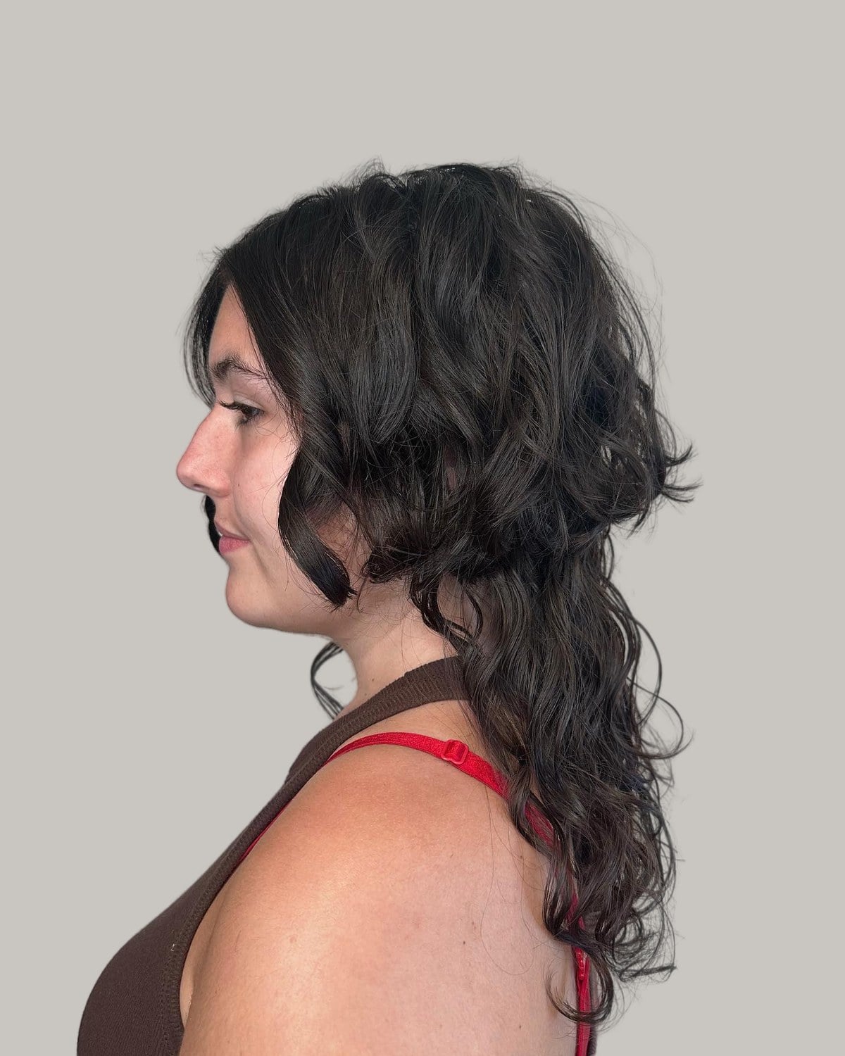 Woman in profile with dark curly hair cut short at the jaw over long curls