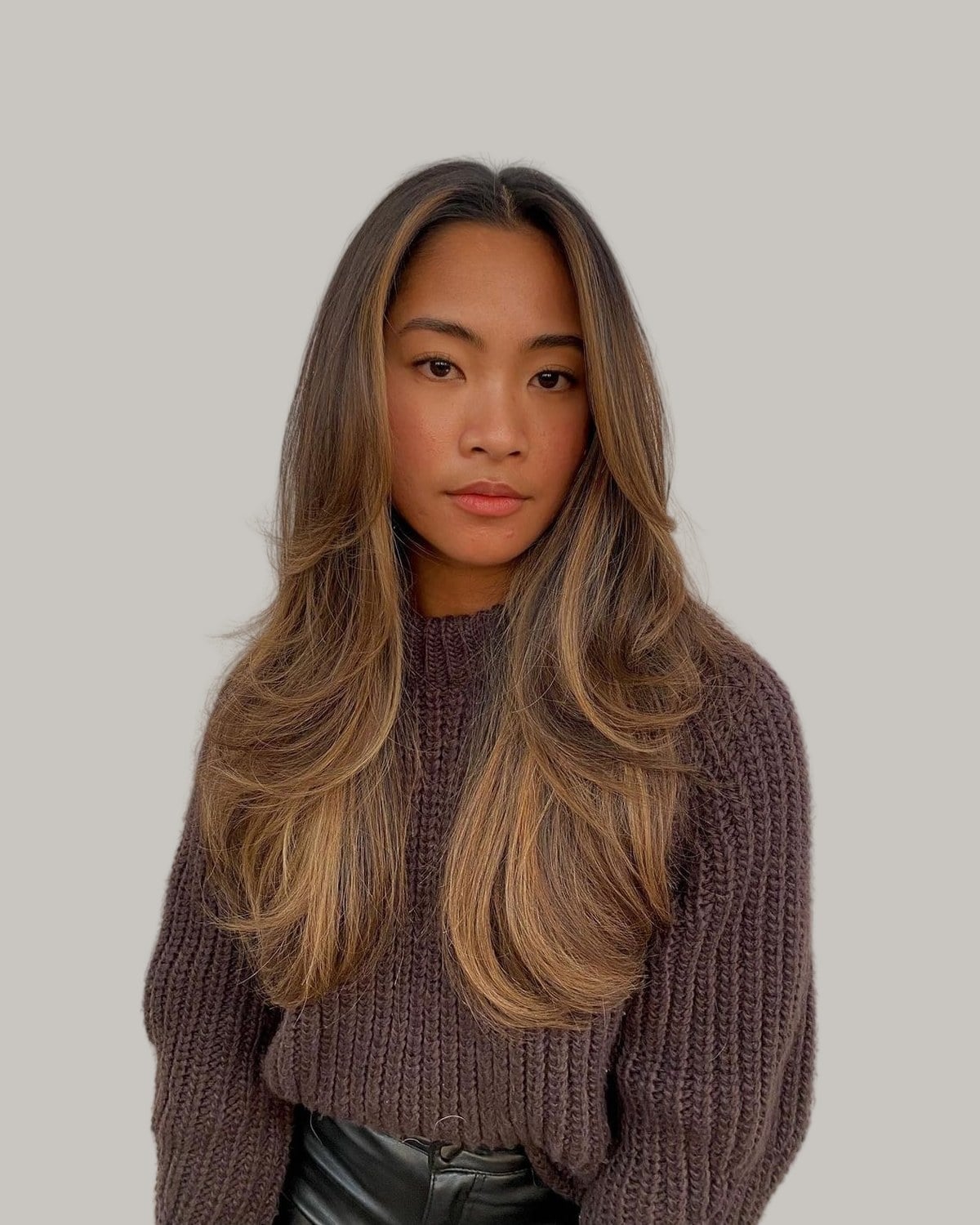 Woman with long brown hair and caramel pieces around her face