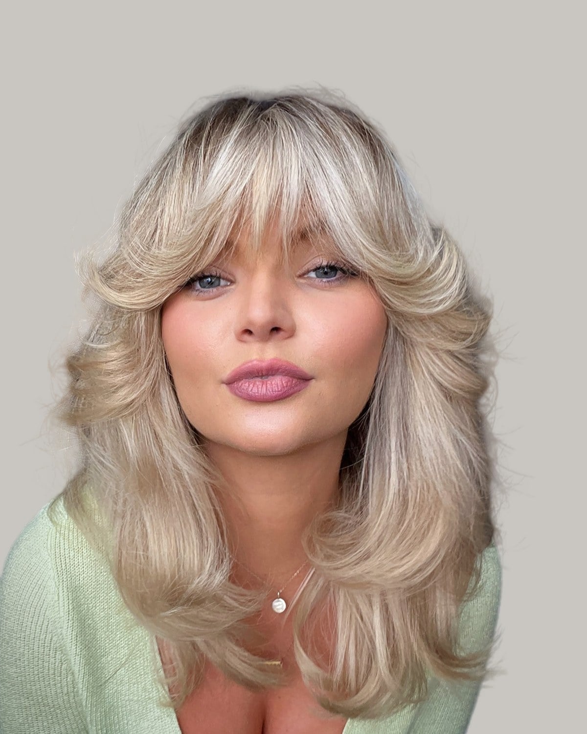 Woman with blonde feathered layers and bangs