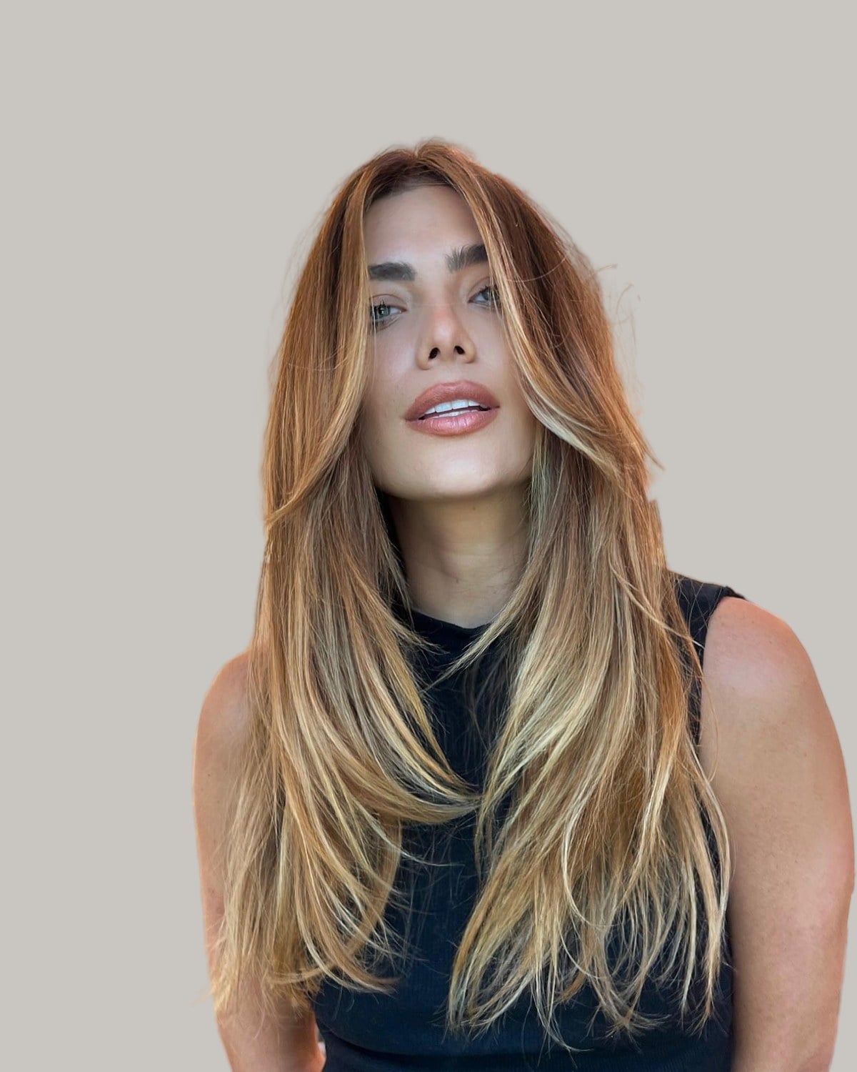 Woman with long, straight caramel-blonde hair and a center part, in a black top