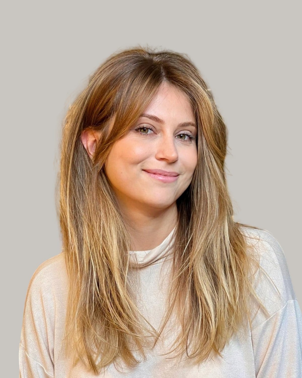 Smiling woman with long honey-blonde hair and wispy front pieces